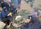 فلسطينيات نازحات يعددن ما يسمى شعبيا "خبز الصاج" في مخيم للنازحين غرب مدينة رفح أقصى جنوب قطاع غزة على الحدود مع مصر (الجزيرة)