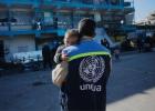 موظف في الأونروا يحمل طفلا صغيرا