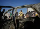 فلسطيني يتفحص سيارة تعرضت لغارة إسرائيلية في مخيم المغازي وسط قطاع غزة (أ.ب)
