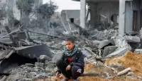 طفل فلسطيني يجلس وسط أنقاض منزل دمرته غارة إسرائيلية في مدينة رفح بجنوب قطاع غزة. 23 فبراير 2024 - Reuters