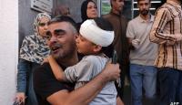 رجل فلسطيني يحمل صبيًا بعد أن عولج من إصابة في الرأس في المستشفى، في أعقاب غارة جوية إسرائيلية على رفح بجنوب قطاع غزة في 23 أكتوبر 2023.