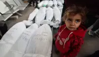 طفلة تقف بجوار جثامين اقاربها