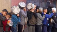أطفال فلسطينيون ينتظرون الحصول على طعام من جمعية خيرية في رفح (رويترز)