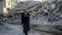 سيدة فلسطينية تسير بين ركام البيوت
