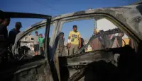 فلسطيني يتفحص سيارة تعرضت لغارة إسرائيلية في مخيم المغازي وسط قطاع غزة (أ.ب)