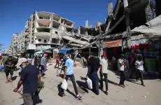 فلسطينيون يمرون أمام مبنى مدمر في سوق مؤقت بمخيم النصيرات للاجئين وسط قطاع غزة