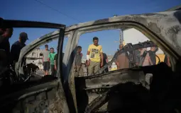 فلسطيني يتفحص سيارة تعرضت لغارة إسرائيلية في مخيم المغازي وسط قطاع غزة (أ.ب)