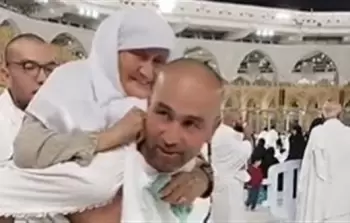 شاب يحمل والدته أمام الحرم المكي