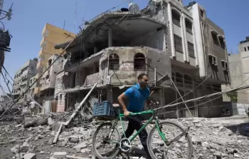 رجل فلسطيني يدفع دراجته وسط الركام في أعقاب غارة عسكرية إسرائيلية على مدينة غزة ، في 23 يوليو / تموز 2014. © أ ف ب/أرشيف