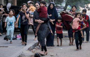 سيدة فلسطينية تحمل طفلها هربا من القصف الاسرائيلي