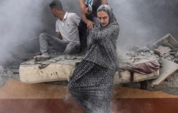 سيدة تحمل نجلها عقب قصف إسرائيلي