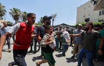 مواطنون يحملون طفلا بعد اصابته في قصف اسرائيلي