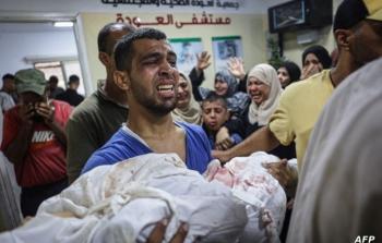 مواطن يحمل طفله بعد قصف الاحتلال لمنازلهم
