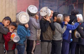 أطفال فلسطينيون ينتظرون الحصول على طعام من جمعية خيرية في رفح (رويترز)