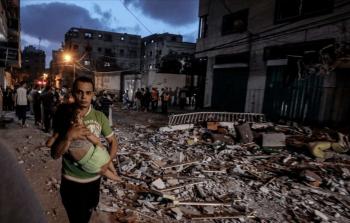 فلسطيني يحمل طفله بعد قصف إسرائيلي على غزة (علي جادالله - الأناضول)