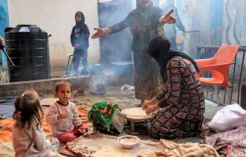 أم تعد الخبز التقليدي لإطعام صغارها في غزة