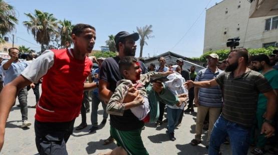 موتطن يحمل طفل مصاب جراء القصف الإسرائيلي