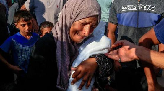 امرأة تحمل طفل استشهد جراء التجويع