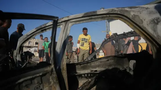 فلسطيني يتفحص سيارة تعرضت لغارة إسرائيلية في مخيم المغازي وسط قطاع غزة (أ.ب)