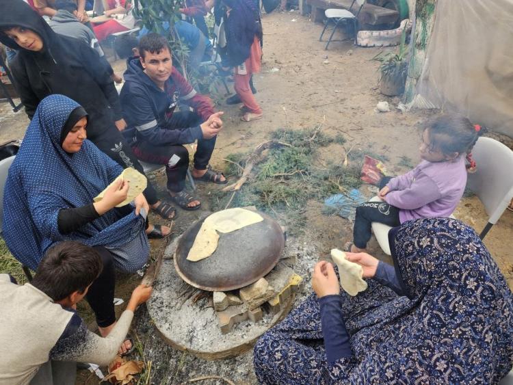 فلسطينيات نازحات يعددن ما يسمى شعبيا "خبز الصاج" في مخيم للنازحين غرب مدينة رفح أقصى جنوب قطاع غزة على الحدود مع مصر (الجزيرة)