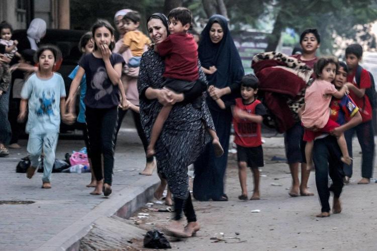 سيدة فلسطينية تحمل طفلها هربا من القصف الاسرائيلي