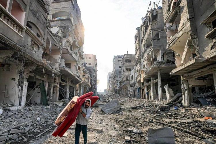 مواطن يحمل فراشه في قطاع غزة