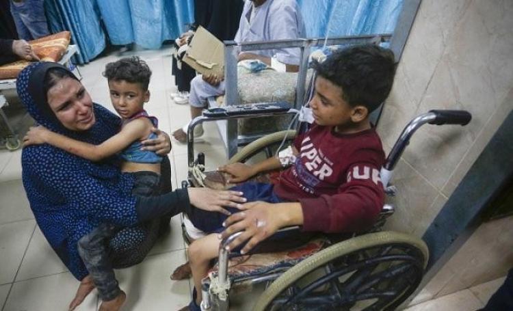 ام تحاول تهدئة أطفالها بعد قصف الاحتلال