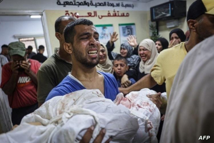 مواطن يحمل طفله بعد قصف الاحتلال لمنازلهم