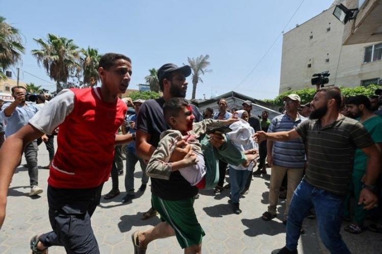 موتطن يحمل طفل مصاب جراء القصف الإسرائيلي