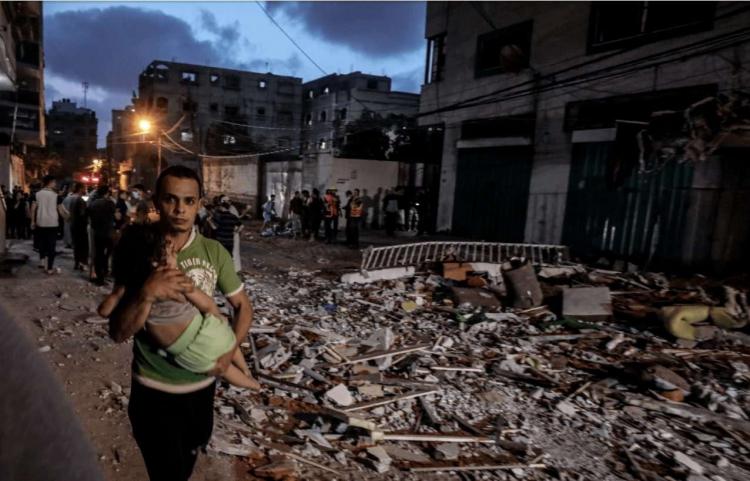 فلسطيني يحمل طفله بعد قصف إسرائيلي على غزة (علي جادالله - الأناضول)