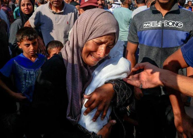 امرأة تحمل طفل استشهد جراء التجويع