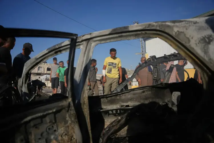 فلسطيني يتفحص سيارة تعرضت لغارة إسرائيلية في مخيم المغازي وسط قطاع غزة (أ.ب)