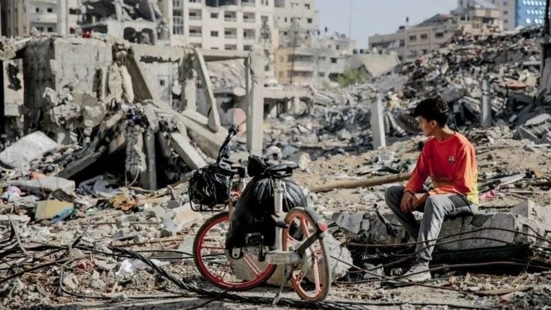 فتى يجلس على ركام منزل في قطاع غزة - GETTY IMAGES
